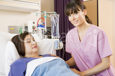 Nurse Helping Senior Woman Lying In Hospital Bed