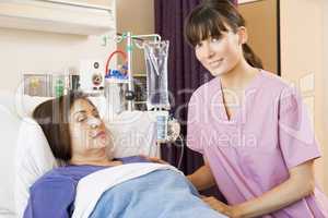 Nurse Helping Senior Woman Lying In Hospital Bed