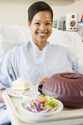 Woman Sitting In Hospital Bed With A Tray Of Food