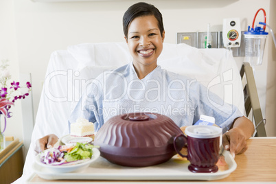 Woman Sitting In Hospital Bed With A Tray Of Food