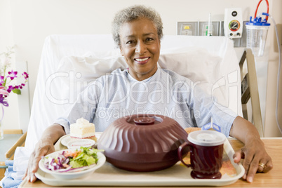 Senior Woman Sitting In Hospital Bed With A Tray Of Food