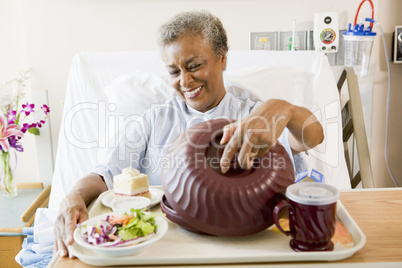 Senior Woman Sitting In Hospital Bed With A Tray Of Food