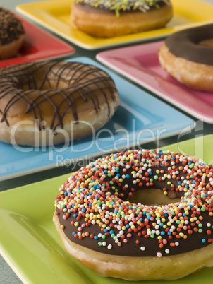Selection Of Ring Doughnuts On A Different Coloured Plates