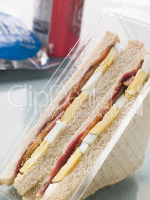 Egg And Bacon Sandwich On White Bread With A Bag Of Crisps And A