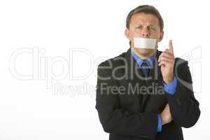 Businessman With His Mouth Taped Shut And Pointing