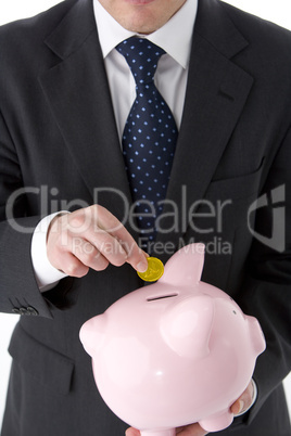 Businessman Putting Coin Into Piggy Bank