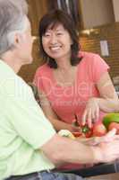 Woman Talking To Husband While Chopping Vegetables