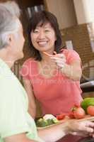 Woman Offering Husband A Piece Of Freshly Chopped Pepper