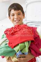 Young Boy Holding A Pile Of Laundry