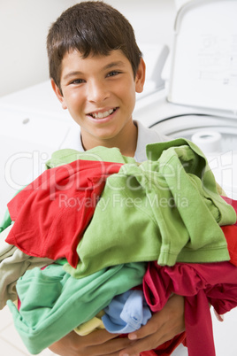 Young Boy Holding A Pile Of Laundry