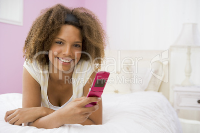 Teenage Girl Lying On Bed Using Mobile Phone