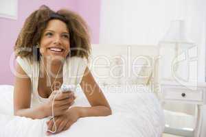 Teenage Girl Lying On Bed Using Mp3 Player