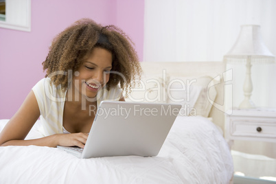 Teenage Girl Lying On Bed Using Laptop