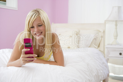 Teenage Girl Lying On Bed Using Mobile Phone