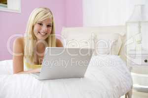 Teenage Girl Lying On Bed Using Laptop