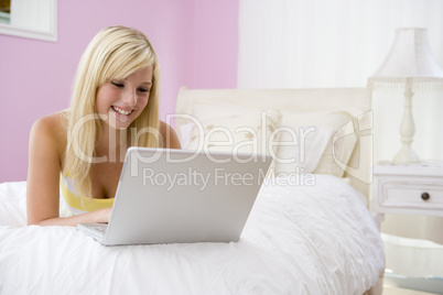 Teenage Girl Lying On Bed Using Laptop