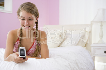 Teenage Girl Lying On Bed Using Mobile Phone