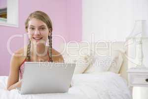 Teenage Girl Lying On Bed Using Laptop