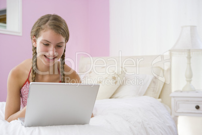 Teenage Girl Lying On Bed Using Laptop