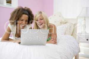 Teenage Girls Lying On Bed Using Laptop