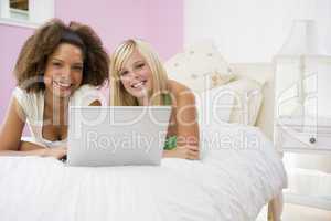Teenage Girls Lying On Bed Using Laptop