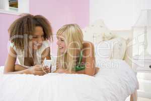 Teenage Girls Lying On Bed Listening To Mp3 Player