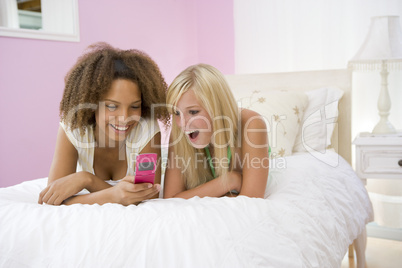 Teenage Girls Lying On Bed Using Cellphone