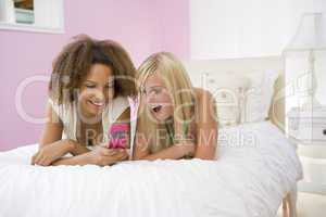 Teenage Girls Lying On Bed Using Cellphone