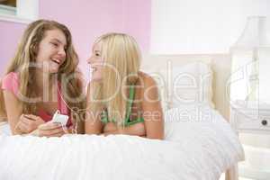 Teenage Girls Lying On Bed Listening To Mp3 Player