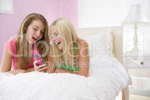 Teenage Girls Lying On Bed Using Cell Phone