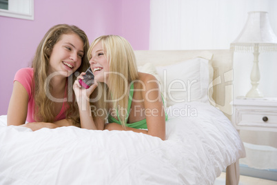 Teenage Girls Lying On Bed Using Cell Phone