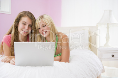 Teenage Girls Lying On Bed Using Laptop