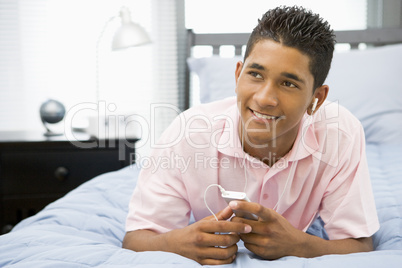 Teenage Boy Lying On Bed Listening To Mp3 Player