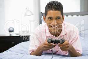 Teenage Boy Lying On Bed Playing Video Game