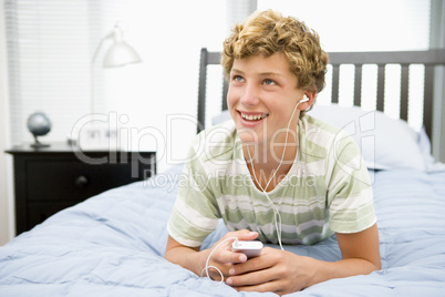 Teenage Boy Lying On Bed Listening To Mp3 Player