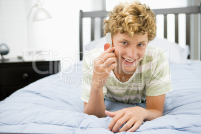 Teenage Boy Lying On Bed Using Mobile Phone