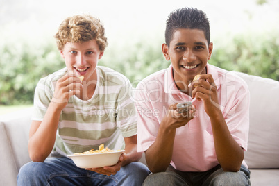 Teenage Boys Sitting On Couch Eating crisps Together