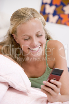 Teenage Girl Lying On Her Bed Using Mobile Phone