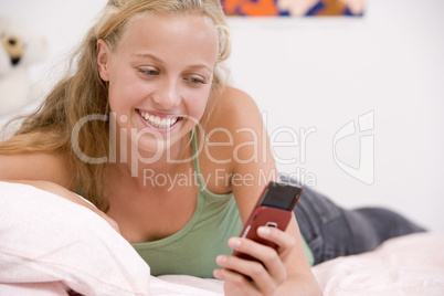 Teenage Girl Lying On Her Bed Using Mobile Phone