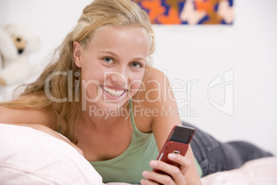 Teenage Girl Lying On Her Bed Using Mobile Phone