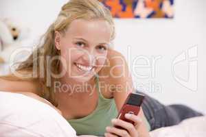 Teenage Girl Lying On Her Bed Using Mobile Phone