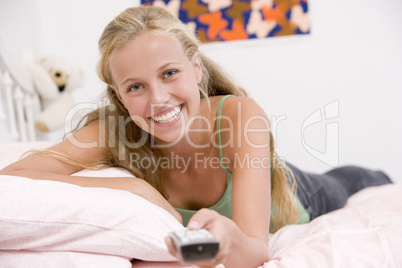 Teenage Girl Lying On Her Bed Changing Television Channels