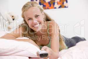 Teenage Girl Lying On Her Bed Changing Television Channels