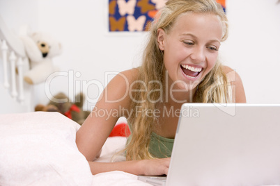 Teenage Girl Lying On Her Bed Using Laptop