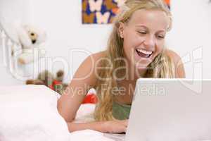 Teenage Girl Lying On Her Bed Using Laptop