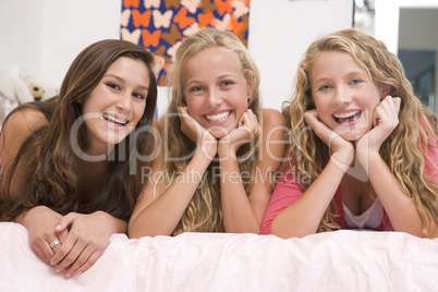 Teenage Girls Lying On Bed Using Mobile Phone