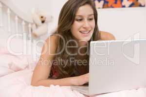 Teenage Girl Lying On Her Bed Using Laptop