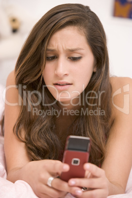 Teenage Girl Lying On Her Bed Using Mobile Phone