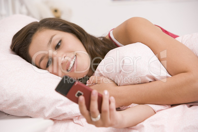 Teenage Girl Lying On Her Bed Using Mobile Phone