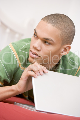 Teenage Boy Lying On Bed Using Laptop